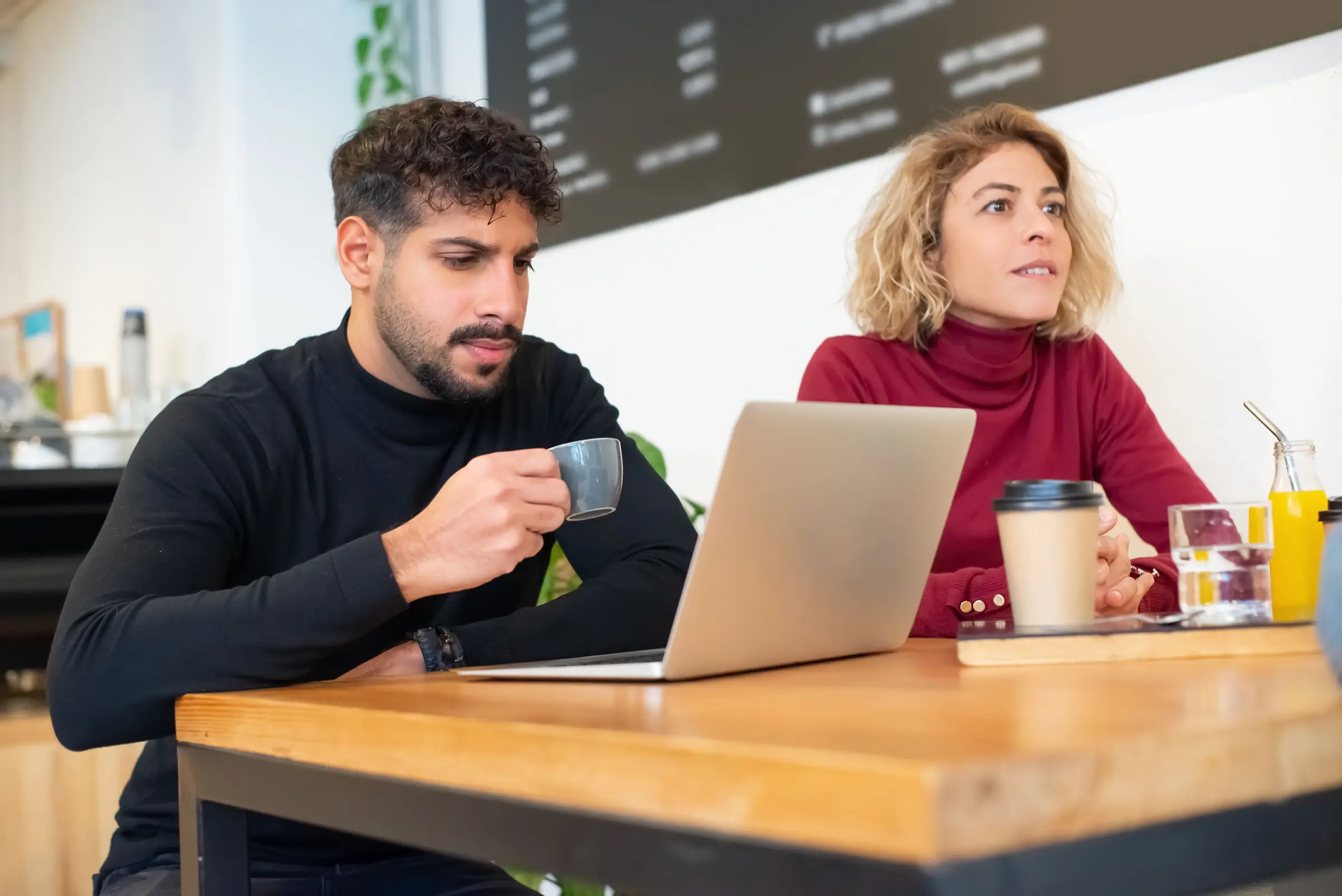 Two people discussing a project over coffee in a café